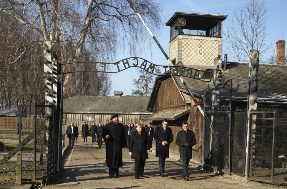 German Chancellor Angela Merkel (2nd L) is flanked by Polish Prime Minister Mateusz Morawiecki (2nd R) and the Director of the Auschwitz-Birkenau State Museum Piotr Cywinski (L) as she walks through the gate during her visit at the former German Nazi death camp Auschwitz-Birkenau in Oswiecim, Poland on December 6, 2019. - Merkel arrived at the Auschwitz former German death camp for her first visit to the site symbolising the Holocaust in her 14 years as chancellor. Merkel is only the third German chancellor ever to visit the camp in Poland, with her landmark trip coming as Germany grapples with a resurgence of anti-Semitism and the growth of the far-right. (Photo by Janek SKARZYNSKI / AFP) (Photo by JANEK SKARZYNSKI/AFP via Getty Images)