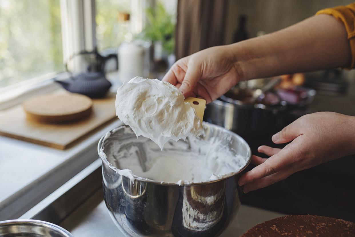 Close up shot of an anonymous young Caucasian woman making whipped cream on a kitchen counter at home