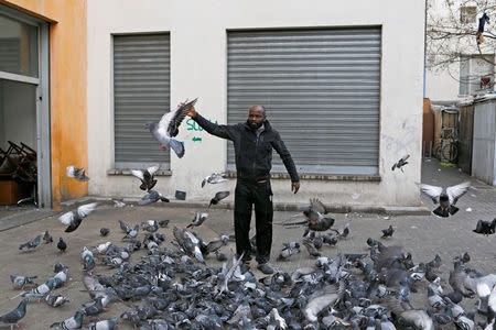 A man feeds pigeons outside one of the four buildings occupied by migrants in the former Olympic village in Turin, Italy January 14, 2018. Picture taken January 14, 2018. REUTERS/Siegfried Modola