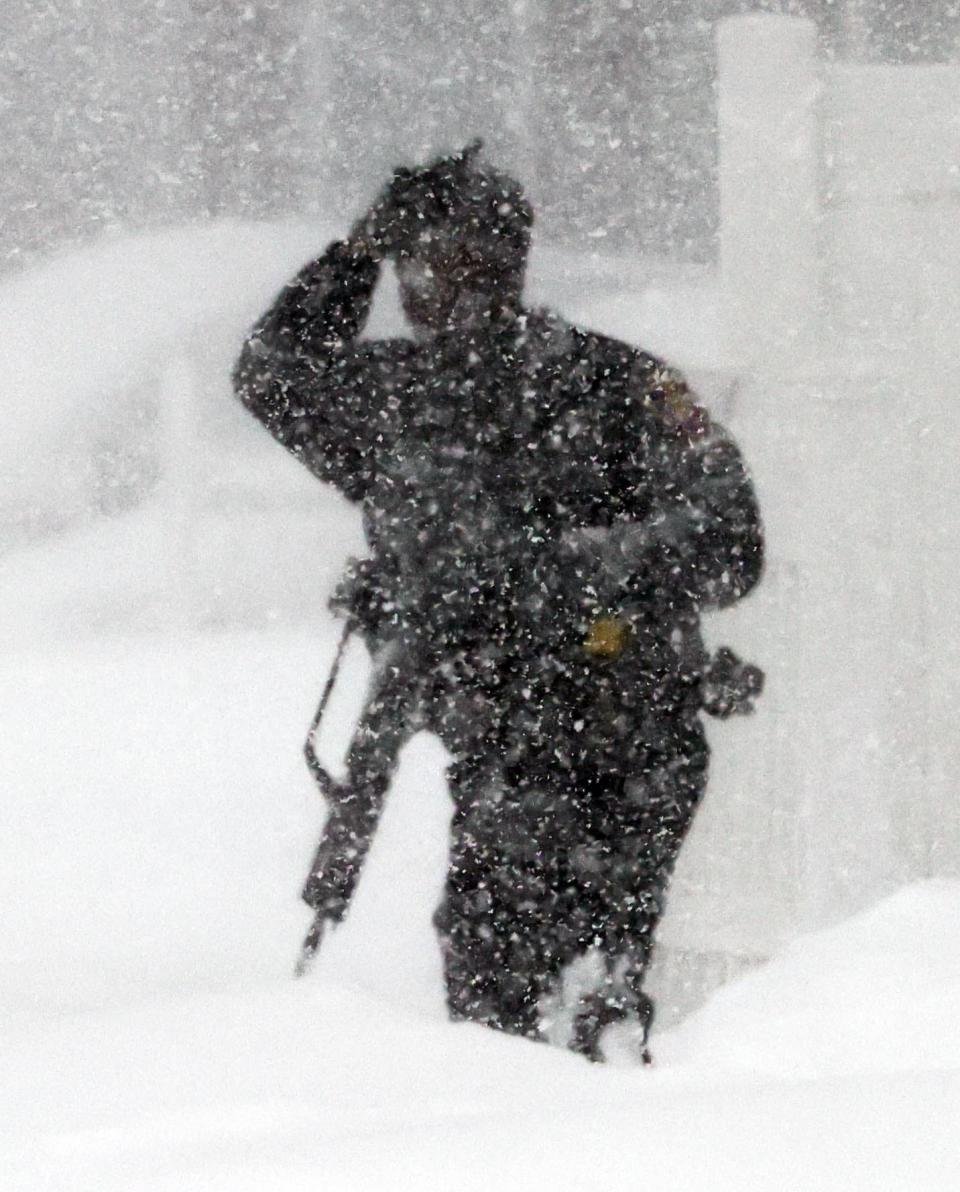 A Brockton police officer holding a rifle is obscured by the snow as police responded to a domestic violence incident with a potentially armed suspect inside a home on Wyman Street on Saturday, Jan. 29, 2022. The incident occurred at the height of the weekend's blizzard.