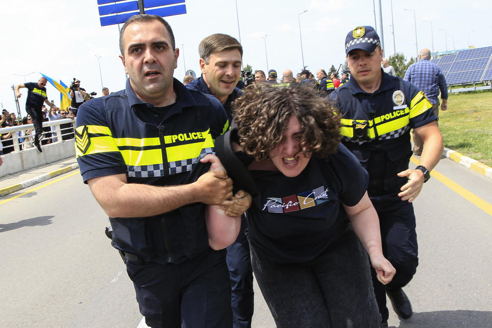 Georgian police detain a demonstrator during a protest against the resumption of air links with Russia at the International Airport outside Tbilisi, Georgia, Friday, May 19, 2023. Direct flights resumed on Friday between Russia and Georgia amid protests and sharp criticism from the South Caucasus nation's president, just over a week after the Kremlin unexpectedly lifted a four-year-old ban despite rocky relations. (AP Photo/Shakh Aivazov)