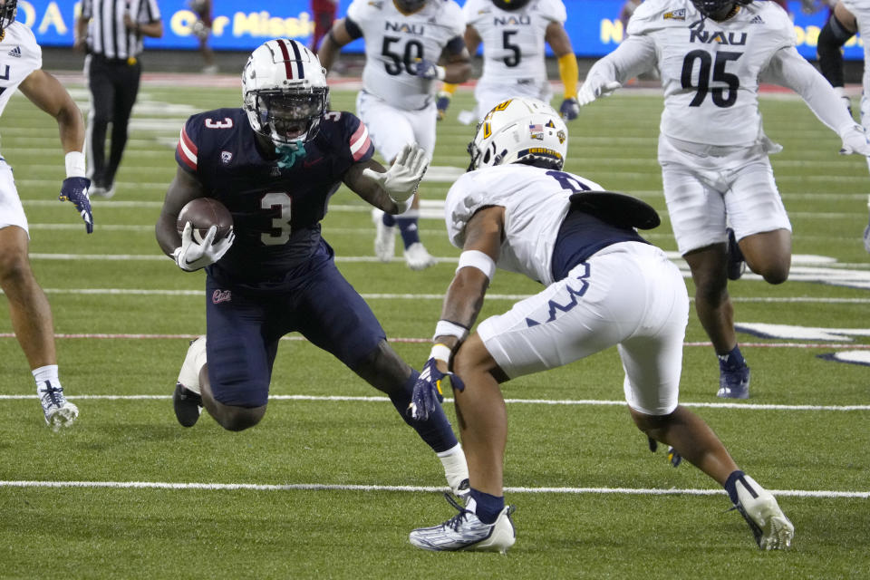 Arizona running back Jonah Coleman (3) looks to fend off Northern Arizona defensive back Shawn Dourseau (0) during the first half of an NCAA college football game Saturday, Sept. 2, 2023, in Tucson, Ariz. (AP Photo/Rick Scuteri)