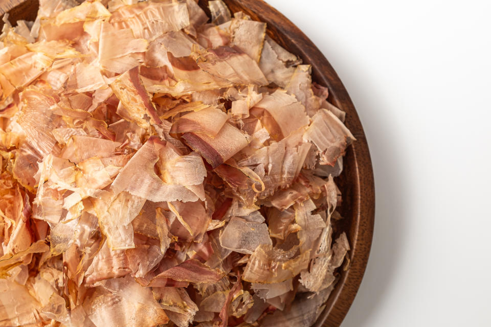 A wooden plate filled with thinly shaved dried bonito flakes