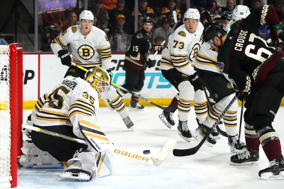 Boston Bruins goaltender Linus Ullmark (35) blocks a shot by Arizona Coyotes left wing Lawson Crouse (67) as Bruins defensemen Mason Lohrei (6) and Charlie McAvoy (73) look on during the first period of an NHL hockey game Tuesday, Jan. 9, 2024, in Tempe, Ariz. (AP Photo/Ross D. Franklin)