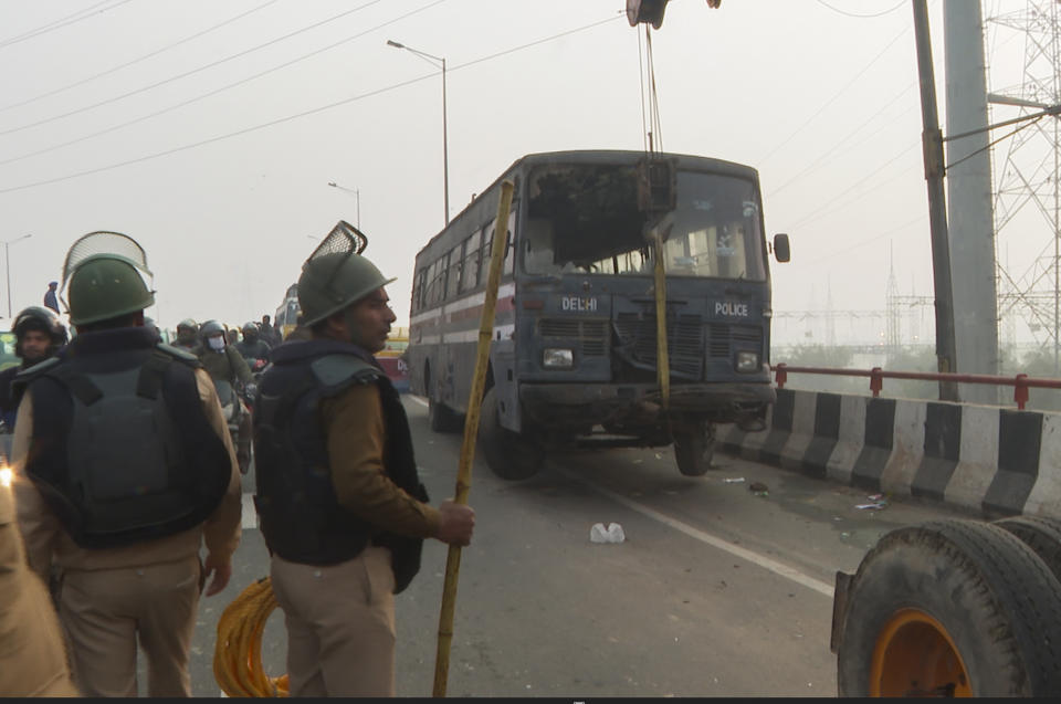 Police lift a vehicle to barricade a major highway at Ghazipur near New Delhi to stop thousands of protesting farmers from entering the capital , India, Tuesday, Feb.13, 2024. (AP Photo/Shonal Ganguly)