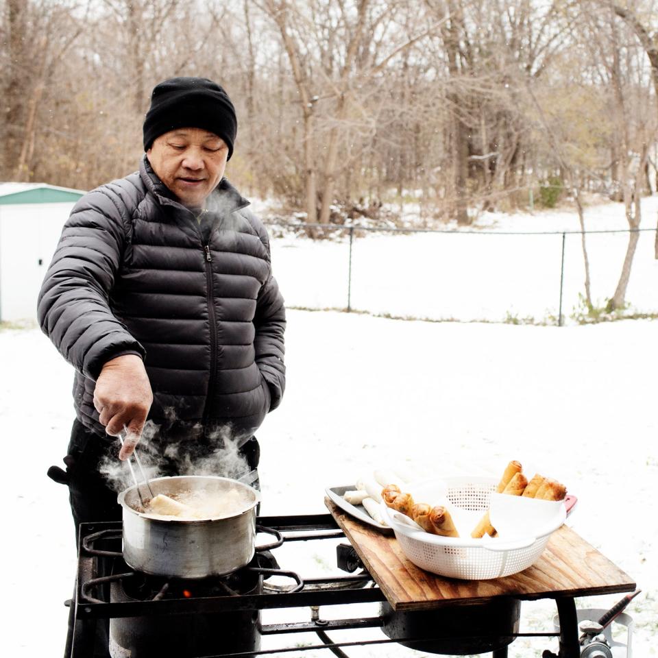 Yia’s father, Nhia Vang, fries egg rolls in his backyard in Hugo, Minnesota.