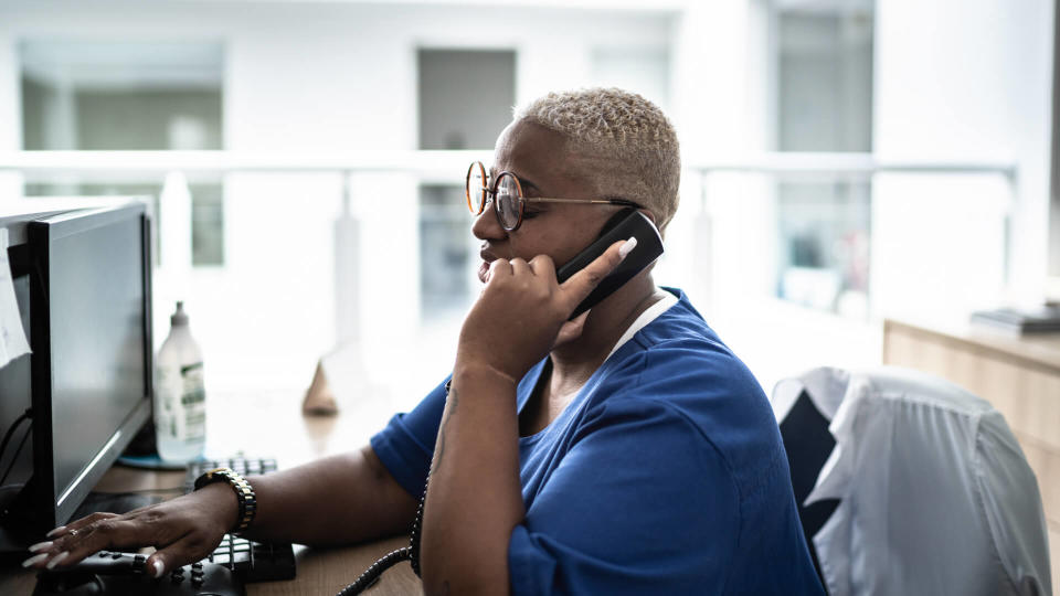 Secretary talking on telephone at hospital reception.