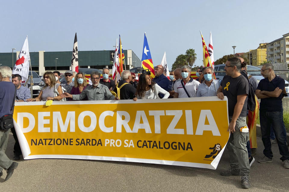 Demonstrators hold a banner with writing reading in a Sardinian dialect, ”Democracy, the Sardinian nation supports the Catalan nation", as they stand outside a court in Sassari, in Sardinia, Italy, Friday, Sept. 24, 2021. Former Catalan leader Carles Puigdemont, sought by Spain for a failed 2017 secession bid, on Friday awaited his opportunity to appear in court to argue against extradition, a day after Italian police detained him in Sardinia, an Italian island with strong Catalan cultural roots and its own independence movement. (AP Photo/Gloria Calvi)