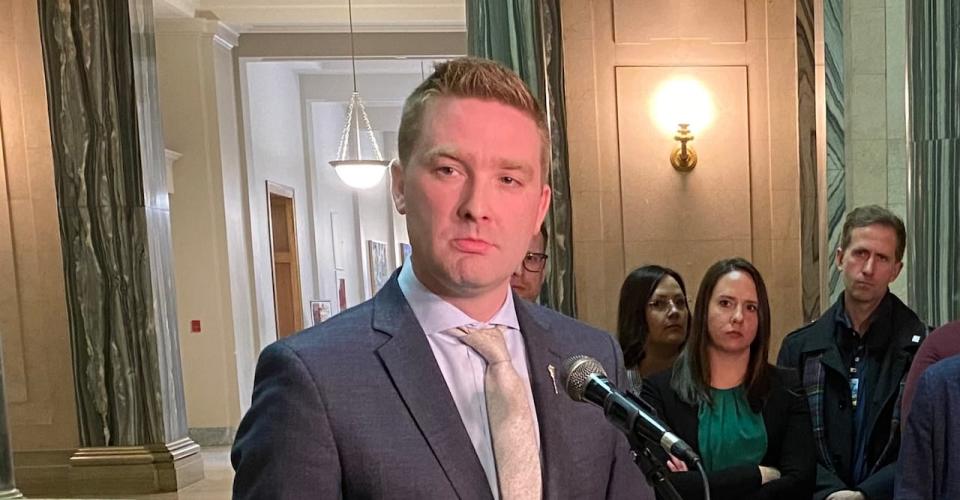 Saskatchewan Education Minister Jeremy Cockrill speaks to media as Saskatchewan Teachers Federation president Samantha Becotte and other members of the STF look on. 