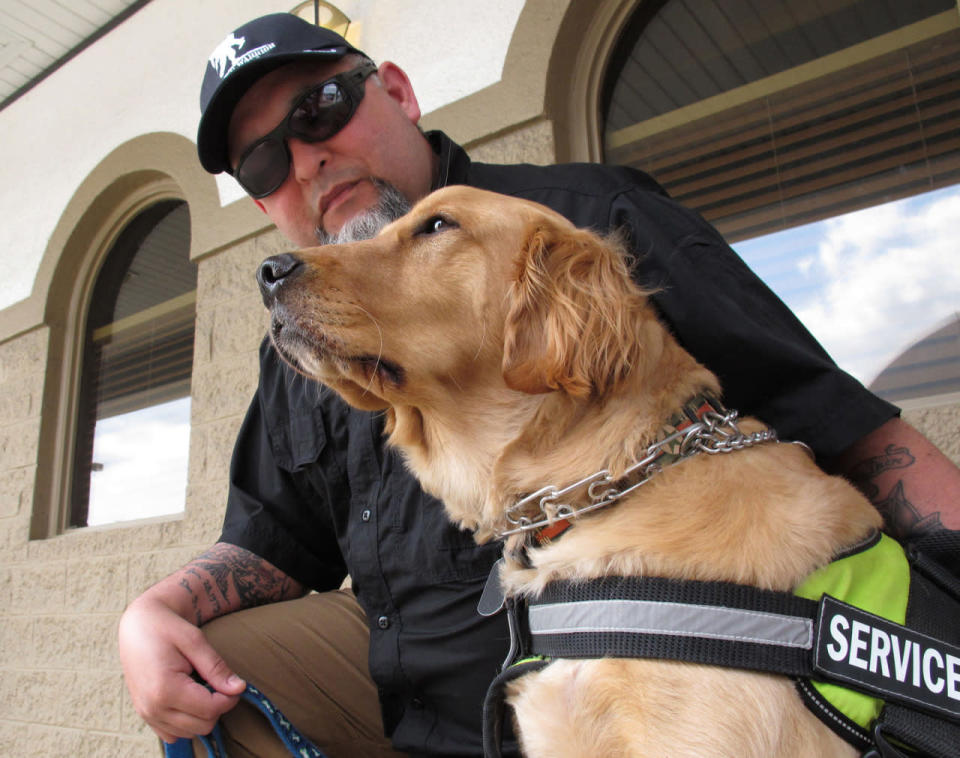 <p>In this Thursday, March 24, 2016 photo, Army veteran Joe Aguirre drapes a tattooed arm across the back of his service dog, Munger, in Fayetteville, N.C. The Department of Veterans Affairs is in the middle of a multi-year study to determine whether it should pay for such psychiatric service dogs. (AP Photo/Allen G. Breed)</p>