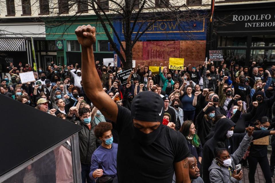 A crowd throws up their fist while gathered outside of the Grand Rapids Police Department to protest in downtown Grand Rapids on Wednesday, April 13, 2022.