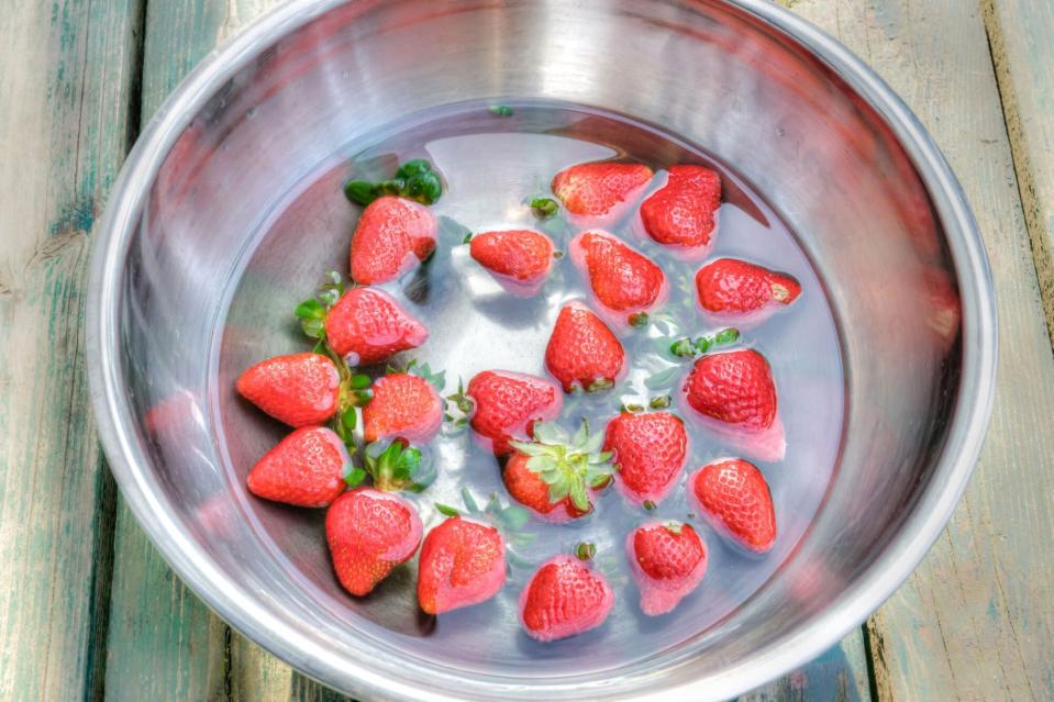 Strawberries soaked in water in a metal bowl