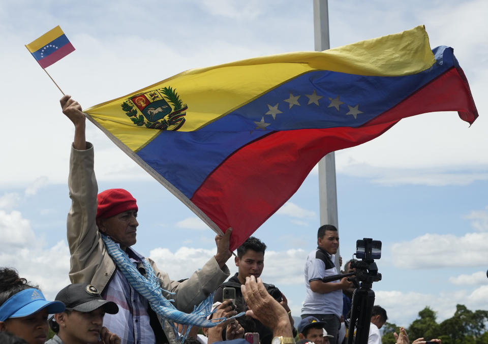 A man holds a Venezuelan flag on the Simon Bolivar International Bridge during a ceremony to mark its reopening to cargo trucks between Cucuta, Colombia and San Antonio del Tachira, Venezuela, Monday, Sept. 26, 2022. Vehicles with merchandise will cross the bridge on Monday in a ceremonial act to seal the resumption of commercial relations between the two nations. (AP Photo/Fernando Vergara)