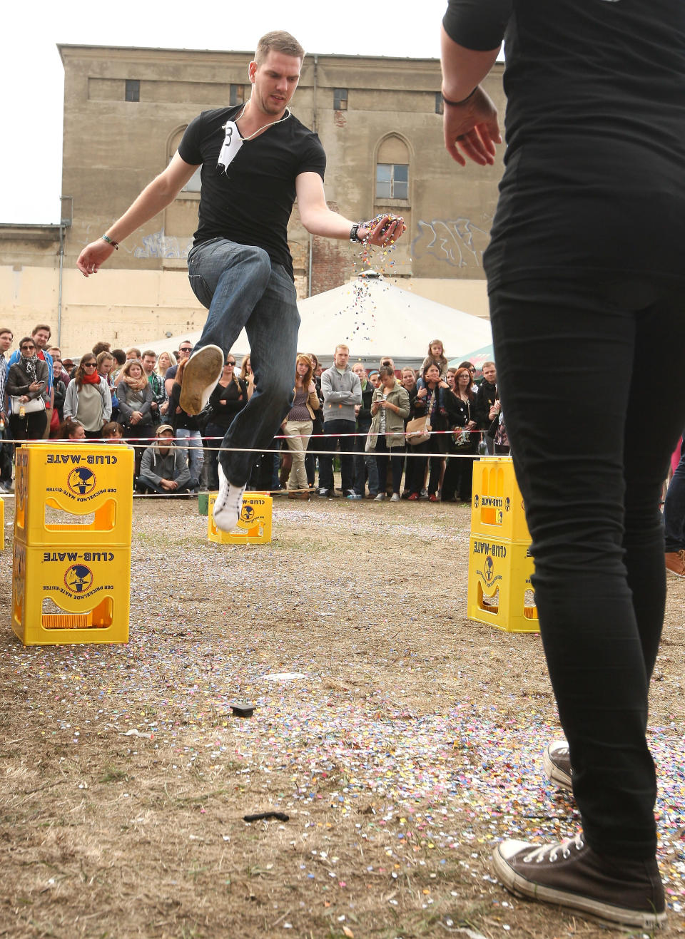 BERLIN, GERMANY - JULY 21: Contestants compete in the "Confetti Toss" event, in which competitors must jump over sticks laid across empty Club-Mate crates and pass confetti to one another, at the second annual Hipster Olympics on July 21, 2012 in Berlin, Germany. With events such as the "Horn-Rimmed Glasses Throw," "Skinny Jeans Tug-O-War," "Vinyl Record Spinning Contest" and "Cloth Tote Sack Race," the Hipster Olympics both mocks and celebrates the Hipster subculture, which some critics claim could never be accurately defined and others that it never existed in the first place. The imprecise nature of determining what makes one a member means that the symptomatic elements of adherants to the group vary in each country, but the archetype of the version in Berlin, one of the more popular locations for those following its lifestyle, along with London and Brooklyn, includes a penchant for canvas tote bags, the carbonated yerba mate drink Club Mate, analogue film cameras, asymmetrical haircuts, 80s neon fashion, and, allegedly, a heavy dose of irony. To some in Berlin, members of the hipster "movement" have replaced a former unwanted identity in gentrifying neighborhoods, the Yuppie, for targets of criticism, as landlords raise rents in the areas to which they relocate, particularly the up-and-coming neighborhood of Neukoelln. (Photo by Adam Berry/Getty Images)