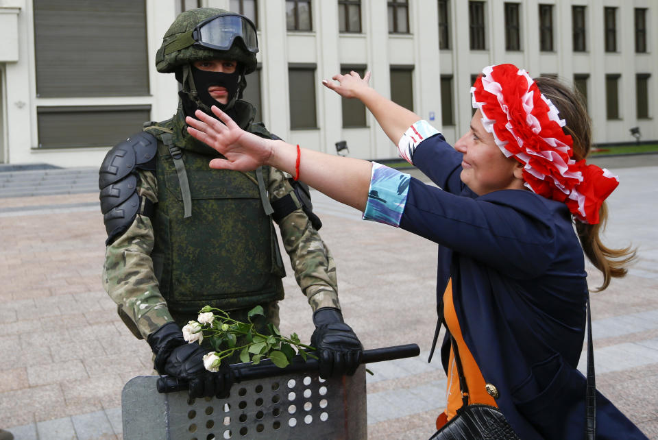 A woman embraces a soldier guarding the Belarusian Government building, in an exaggerated show of friendliness, in Minsk, Belarus, Friday, Aug. 14, 2020. Some thousands of people have gathered in the centre of the Belarus capital, Minsk, in a show of anger over a recent brutal police crackdown on peaceful protesters that followed a disputed presidential election. (AP Photo/Sergei Grits)