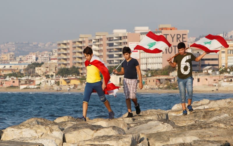 Youths carry Lebanese flags during an anti-government protest in the southern city of Nabatiyeh, Lebanon