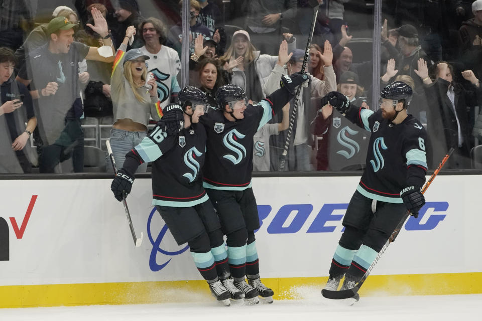 Seattle Kraken center Ryan Donato, center, celebrates with teammates Jared McCann (16) and Adam Larsson (6) after Donato scored a goal against the Montreal Canadiens during the third period of an NHL hockey game, Tuesday, Oct. 26, 2021, in Seattle. The Kraken won 5-1. (AP Photo/Ted S. Warren)