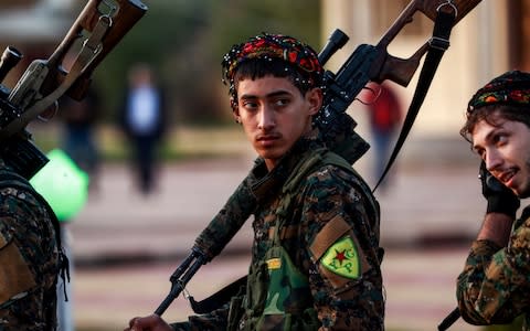 YPG fighter holds a sniper rifle on his shoulder as he attends the funeral of a slain commander in the northeastern city of Qamishli - Credit: AFP