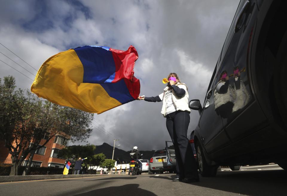 A supporter of former President Alvaro Uribe waving a national flag takes part in a caravan to protest the Supreme Court decision to place Uribe under house arrest while it advances a witness tampering investigation against him, in Bogota, Colombia, Friday, Aug. 7, 2020. (AP Photo/Fernando Vergara)