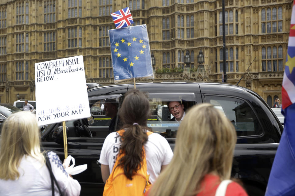 FILE - In this Wednesday, June 20, 2018 file photo, a man in a passing taxi shouts his disagreement at anti-Brexit, pro-EU supporters protesting backdropped by the Houses of Parliament in London. The divisions opened up by the 2016 referendum have not healed, but hardened, splitting Britain into two camps: leavers and remainers. Almost the only thing the two groups share is pessimism about the way Brexit is going. (AP Photo/Matt Dunham)