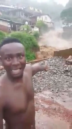 Kelvin Kamara speaks to the camera as he gestures to gushing water in the town of Foulah, following a mudslide on the outskirts of Freetown, Sierra Leone, in this still image obtained from a social media video taken August 14, 2017. Video taken August 14, 2017. Kelvin Kamara and Fuhard Sesay / Social Media Website via REUTERS. THIS IMAGE HAS BEEN SUPPLIED BY A THIRD PARTY. NO RESALES. NO ARCHIVES. MANDATORY CREDIT.