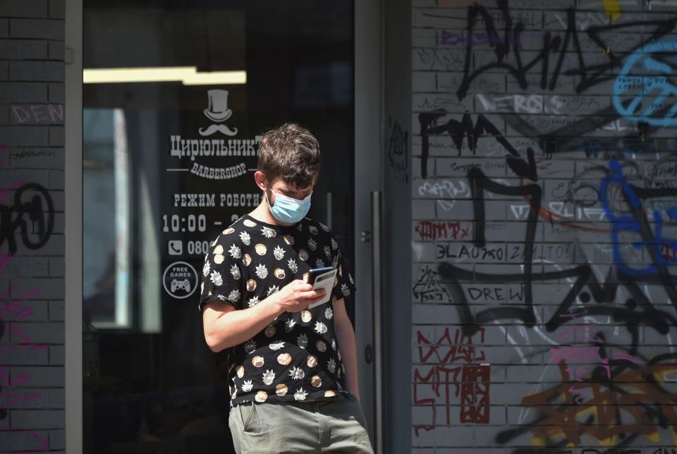 A man wearing a protective face mask, queue outside a barber shop which reopened on May 11, 2020, in Kiev, after months-long closures aimed at stemming the spread of the COVID-19 outbreak, the novel coronavirus. - From May 11 2020 Ukrainians will be allowed to visit outdoor cafes, beauty salons, dental clinics, parks and squares as Ukraine partially lifts some restrictions imposed to curb the spread of the novel coronavirus. (Photo by Sergei SUPINSKY / AFP) (Photo by SERGEI SUPINSKY/AFP via Getty Images)