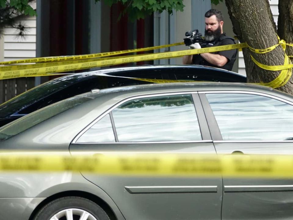 A police officer takes photos on June 28, 2022, at the scene of a triple homicide south of Ottawa's core the previous night. (Francis Ferland/CBC - image credit)