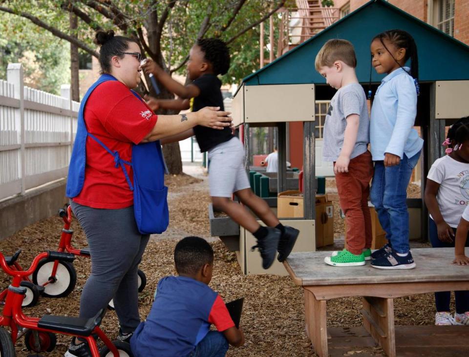 Preschool teacher Leyda Rodriguez catches children as they jump off a very short table at the Rosie K. Mauk Child Development Center in Fort Worth on Wednesday.