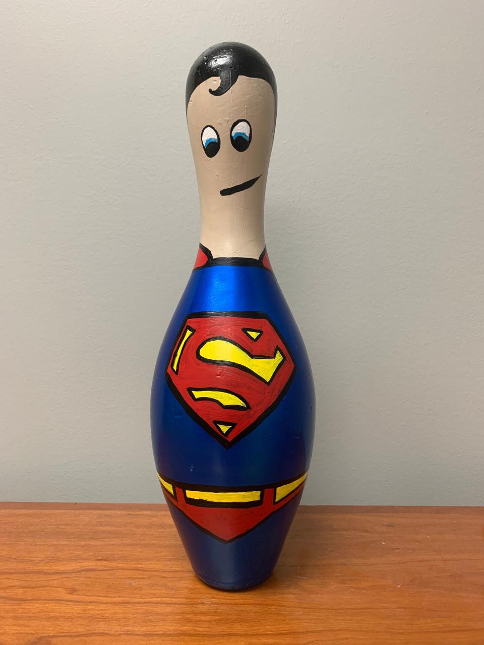 A bowling pin decorated to look like Superman, from a former Pin and Ink Art Showcase.