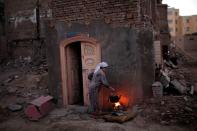 A woman cooks in her house next to the remnants of other houses, demolished as part of a building renovation campaign in the old district of Kashgar