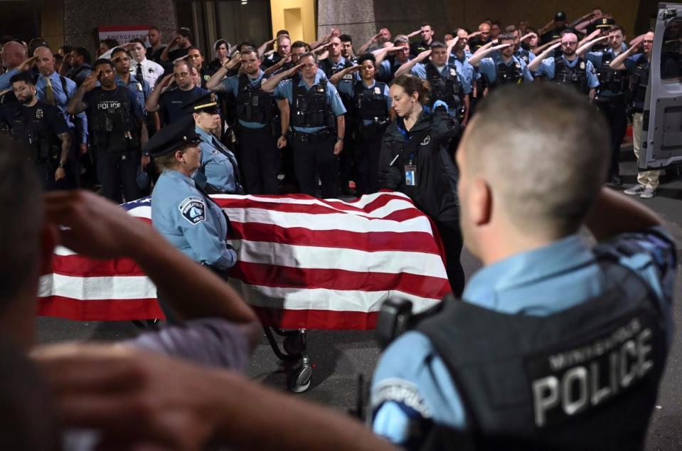 Law enforcement officers salute the flag-draped remains of Jamal Mitchell as he is escorted to a waiting medical examiner's vehicle outside Hennepin County Medical Center (AP)
