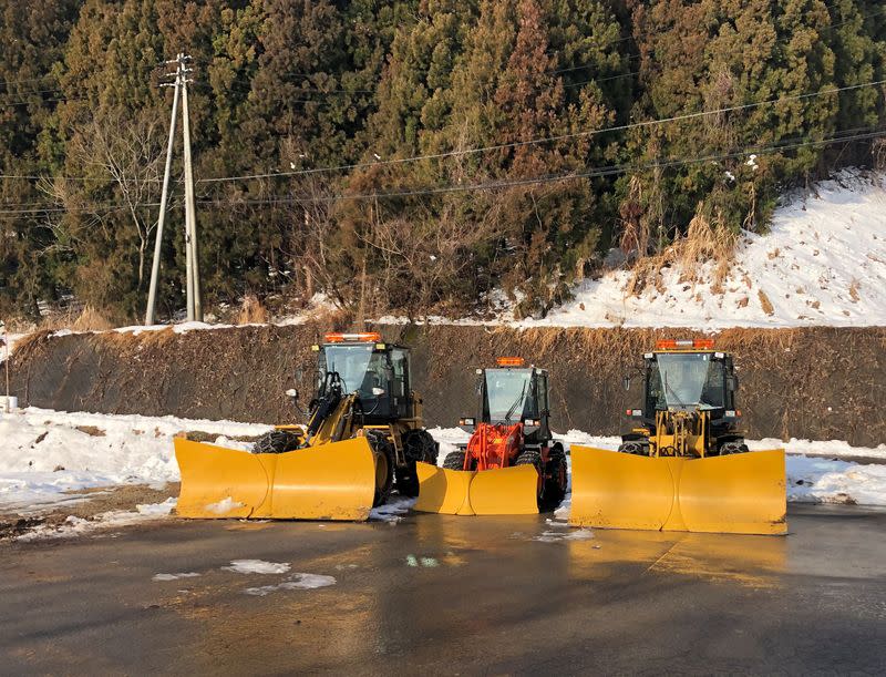 Snow ploughs are parked near a snow resort in Iiyama