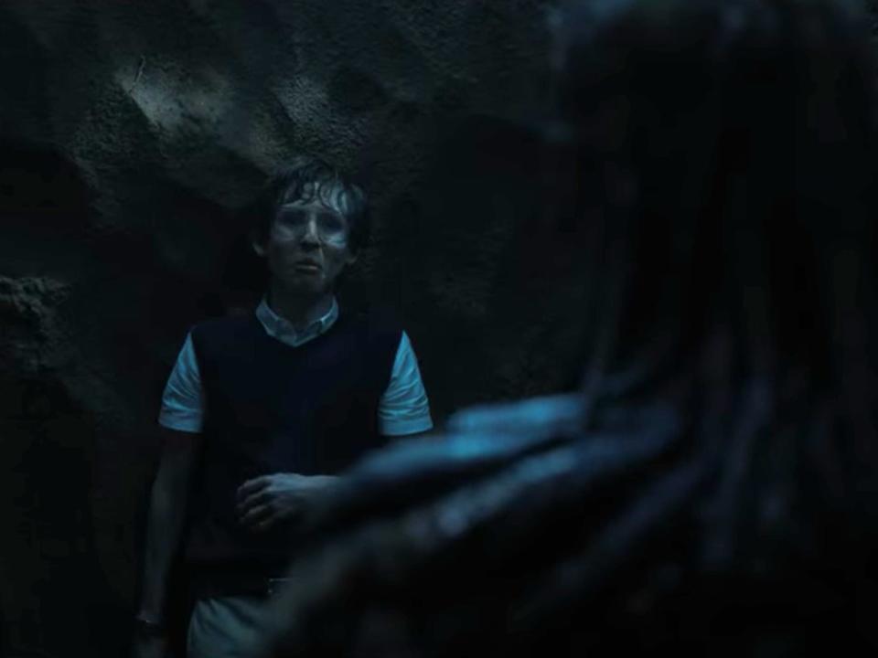 fred benson in stranger things season 4, backed up again st a wall in the forest with vecna's back to the camera