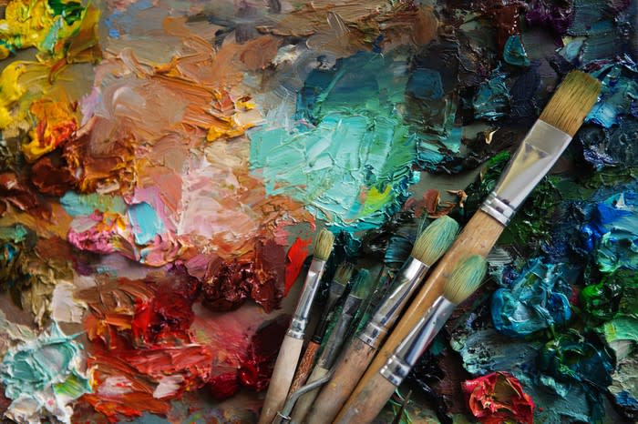 A closeup view of a painting with paintbrushes lying on it