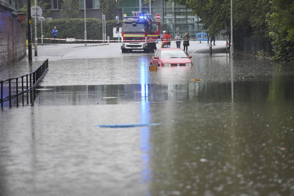 A car is seen stranded in flood water after heavy rain in Manchester, England, Wednesday, July 31, 2019. The UK currently has 10 flood warnings in place from North Yorkshire, Lancashire and the West Midlands. (Jacob King/PA via AP)