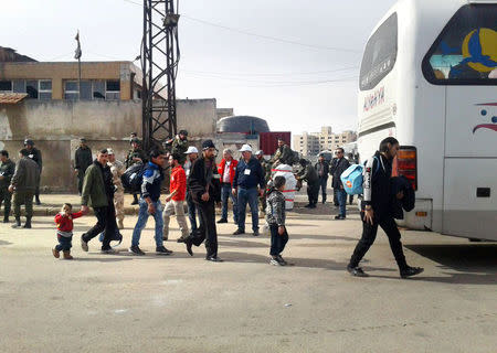 Rebel fighters and their families evacuate the Waer district in the central Syrian city of Homs. SANA/Handout via REUTERS
