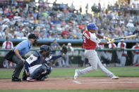 Home plate umpire Brian deBrauwere, left, wears an earpiece as Liberty Division's Tyler Ladendorf, right, of the High Point Rockers, swings at a pitch from Freedom Division's Mitch Atkins, of the York Revolution, during the first inning of the Atlantic League All-Star minor league baseball game, Wednesday, July 10, 2019, in York, Pa. Also seen is catcher James Skelton, center, of the York Revolution. deBrauwere wore the earpiece connected to an iPhone in his ball bag which relayed ball and strike calls upon receiving it from a TrackMan computer system that uses Doppler radar. The independent Atlantic League became the first American professional baseball league to let the computer call balls and strikes during the all star game. (AP Photo/Julio Cortez)