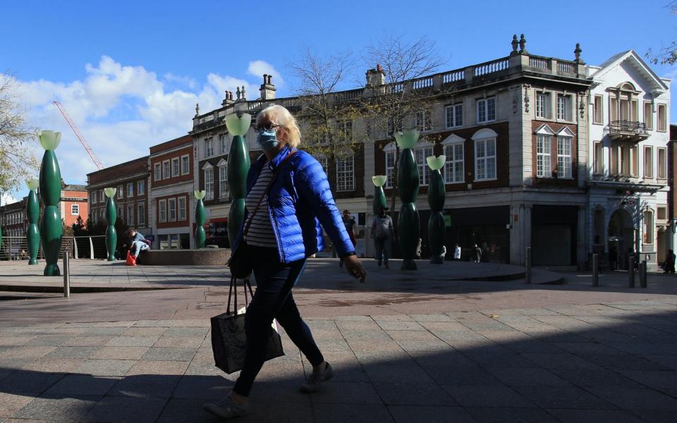 Pedestrians wearing facemasks walk through central Warrington, north west England  - AFP