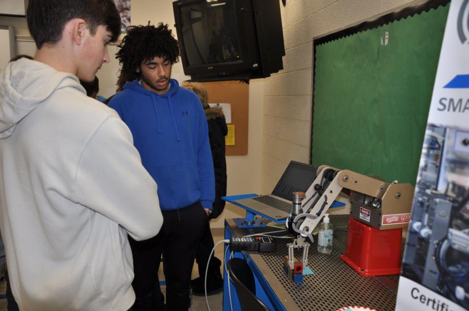 West Branch High School senior Jaxon Robb, 17, and junior Xander Culbertson, 16, watch a robotic arm they coded perform a task with blocks on Thursday, Jan. 11, 2024, part of the school's first Industrial Maintenance Showcase.