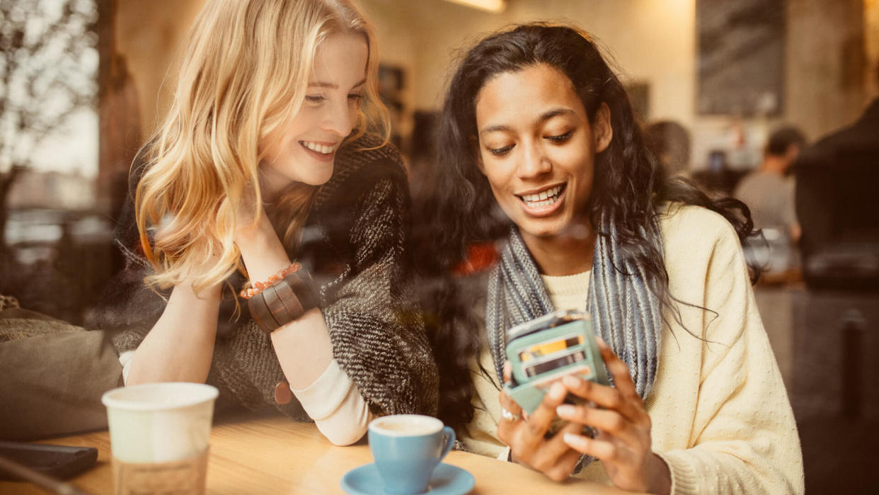 Girlfriends using Smartphone in Coffeeshop.