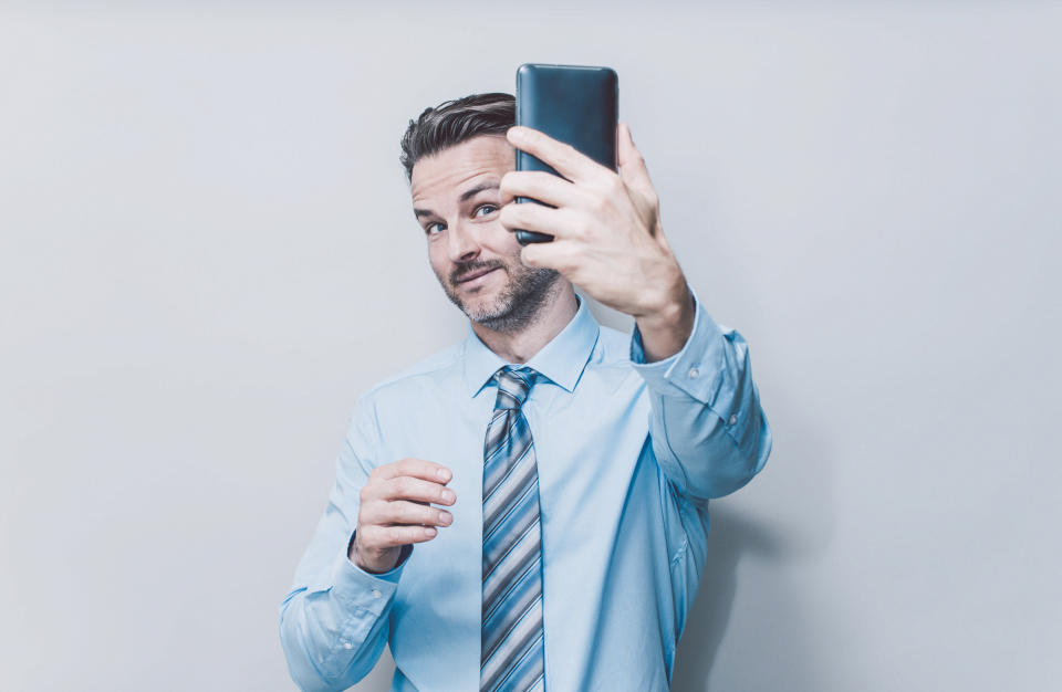 Businessman doing selfie, studio-portrait.