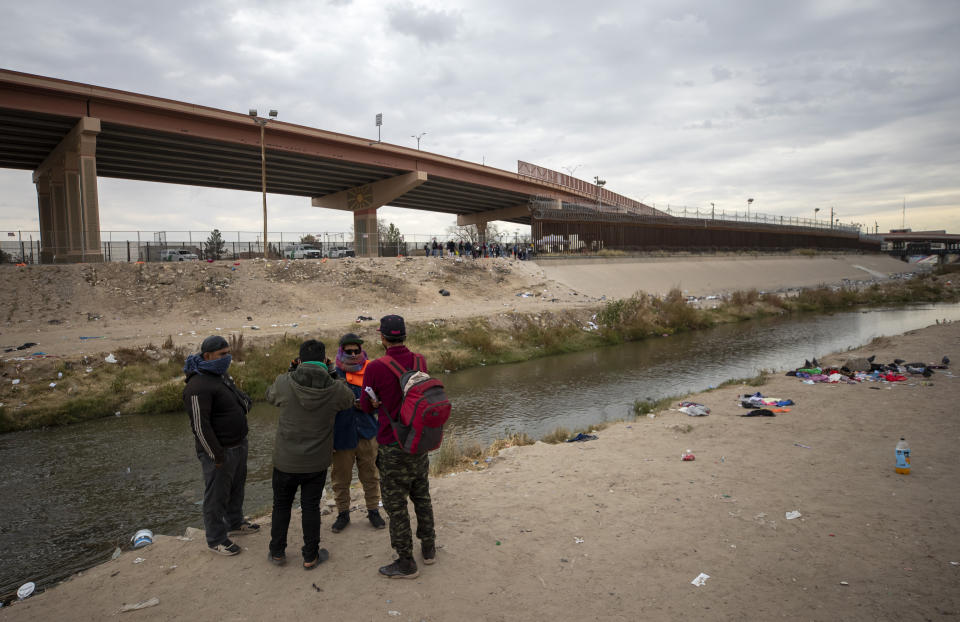 A small group of migrants discuss whether or not to cross the Rio Grande from Ciudad Juarez, Mexico and surrender to the Border Patrol in El Paso, Texas, Sunday, Dec. 18, 2022. Texas border cities were preparing Sunday for a surge of as many as 5,000 new migrants a day across the U.S.-Mexico border as pandemic-era immigration restrictions expire this week, setting in motion plans for providing emergency housing, food and other essentials. (AP Photo/Andres Leighton)
