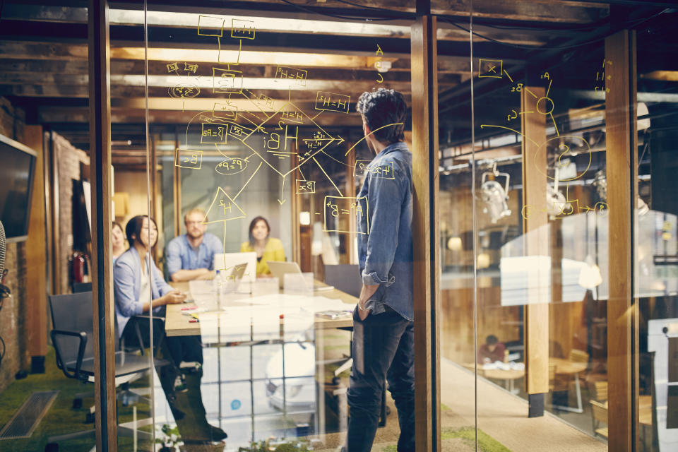 A team of young professionals discuss a project in modern office meeting room.