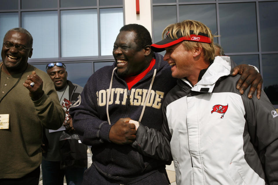 In this Dec. 8, 2006, photo, former Tampa Bay Buccaneers NFL football player David Lewis shakes hands while joking with Tampa Bay Buccaneers head coach Jon Gruden, right, after a Bucs practice in Tampa, Fla. Former Bucs nose tackle Randy Crowder is at far left. Former Bucs defensive player Johnny Ray Smith is at rear, second from left. Lewis, a key member of the Tampa Bay Buccaneers’ 1979 team that reached the NFC title game, has died. He was 65. Lewis died Tuesday, July 14, 2020, in Tampa. The cause was not immediately known, but he had struggled with health issues in recent years, according to Southern California, where he played in college. (Carrie Pratt/Tampa Bay Times via AP)