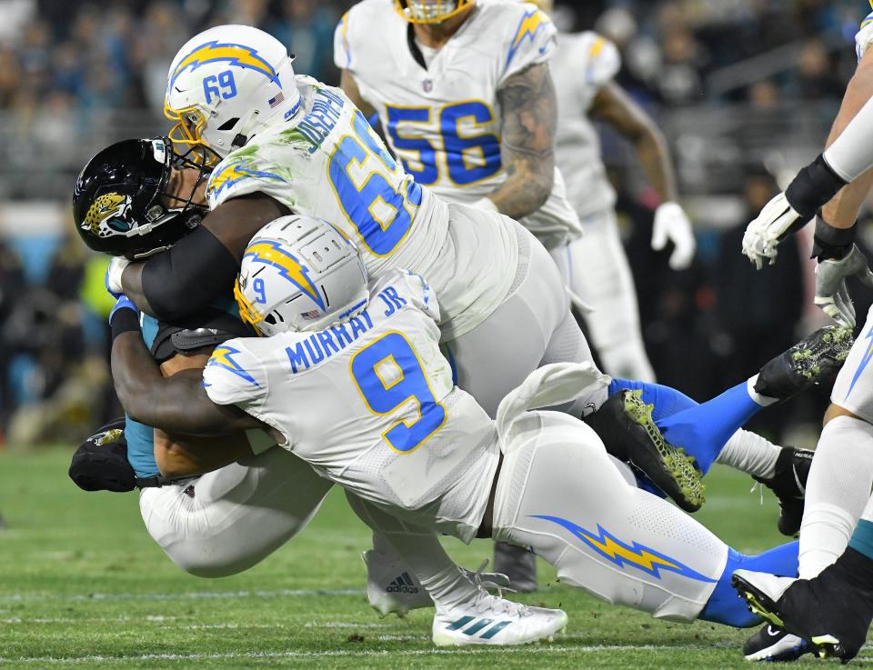 Jacksonville Jaguars quarterback Trevor Lawrence (16) gets sacked by Los Angeles Chargers defensive tackle Sebastian Joseph-Day (69) and linebacker Kenneth Murray Jr. (9) during early second quarter action. The Jacksonville Jaguars hosted the Los Angeles Chargers in their first round playoff game Saturday, January 14, 2023 at TIAA Bank Field in Jacksonville, Fla. The Jaguars trailed 27 to 7 at the half. [Bob Self/Florida Times-Union]