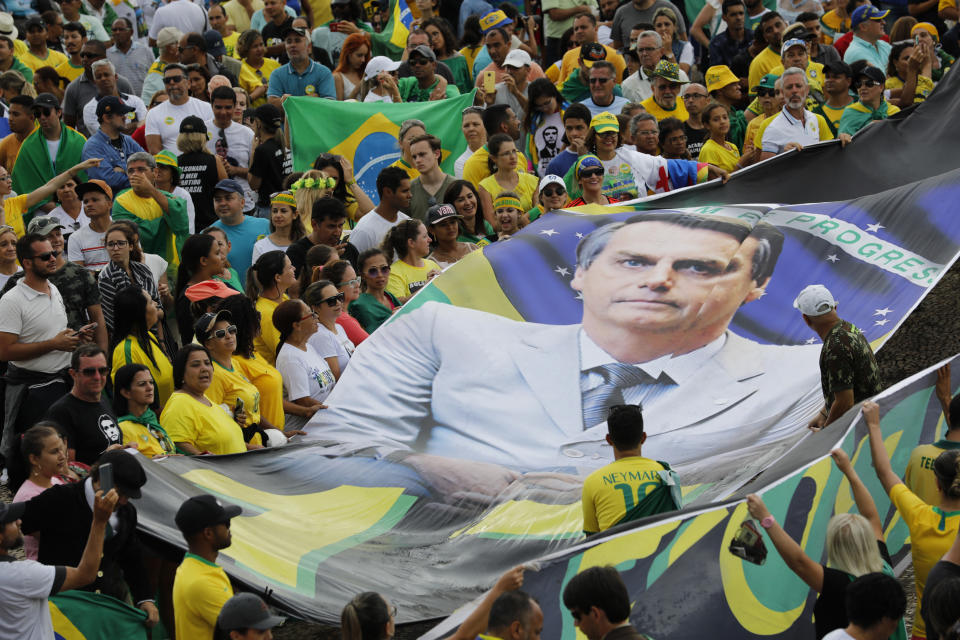 In this Tuesday, Jan. 1, 2019 photo, supporters of Brazil's new President Jair Bolsonaro display a giant banner of him on his inauguration day in Brasilia, Brazil. (AP Photo/Silvia Izquierdo)