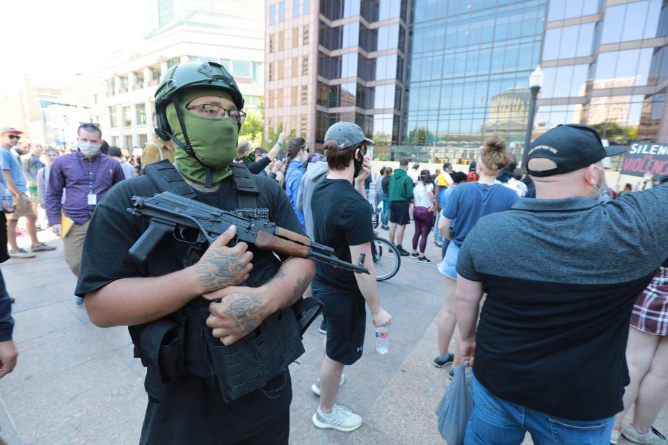 An man who declined to be identified walks through the Ohio Statehouse crowd during a peaceful Sunday, May 31, 2020 protest over the death of George Floyd in Minnesota. He said he was carrying an AK-47 and it was loaded. He said he was not with any particular group.