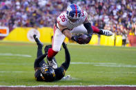 New York Giants running back Saquon Barkley (26) dives into the endzone to score a touchdown against Washington Commanders safety Kamren Curl (31) during the second half of an NFL football game, Sunday, Nov. 19, 2023, in Landover, Md. (AP Photo/Andrew Harnik)