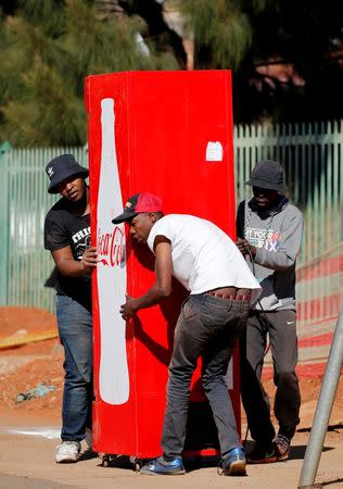 Locals carry a Cocacola branded refrigerator they looted at a nearby shop during protests in Atteridgeville, a township located to the west of Pretoria, South Africa June 21, 2016. REUTERS/Siphiwe Sibeko