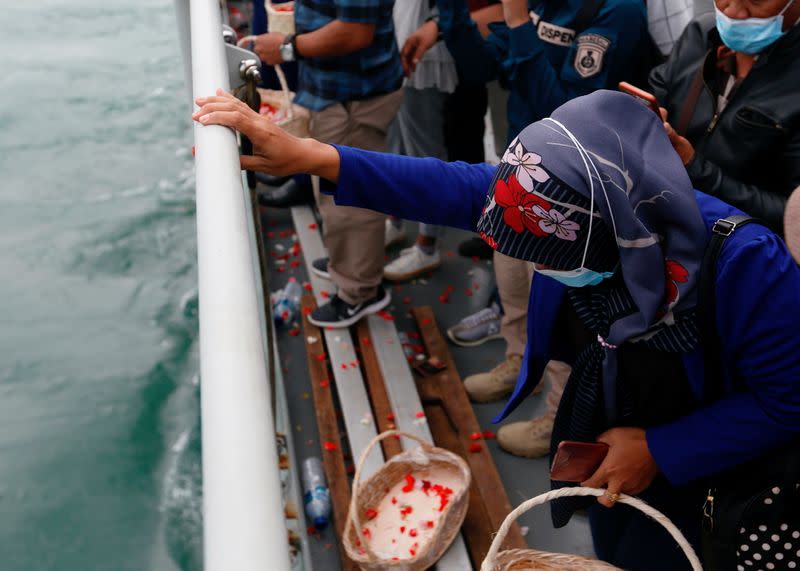 A family member of the passenger of Sriwijaya Air flight SJ 182, which crashed into the sea, mourns while visiting the site of the crash to pay their tribute, on the deck of Indonesia's Naval ship KRI Semarang, at the sea off the Jakarta coast